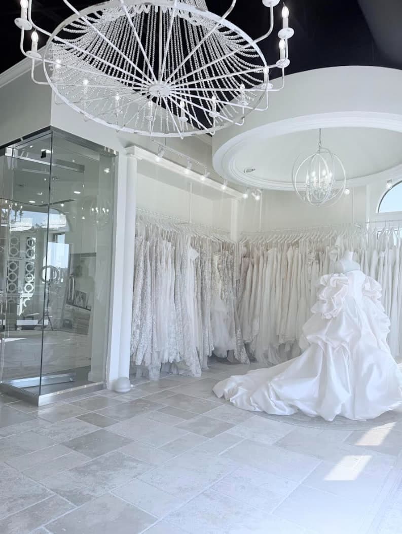 Inside the new Olia Zavozina salon: crystal chandeliers over racks of white gowns, and a ball gown with a long train on a dress form